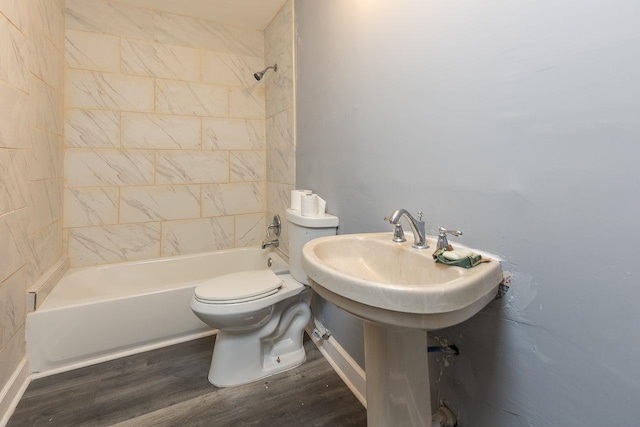 bathroom featuring toilet, tiled shower / bath combo, and hardwood / wood-style floors