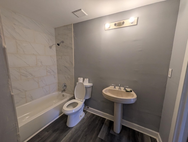 bathroom with hardwood / wood-style flooring, toilet, and tiled shower / bath combo