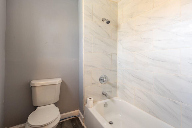 bathroom featuring hardwood / wood-style flooring, toilet, and tiled shower / bath combo