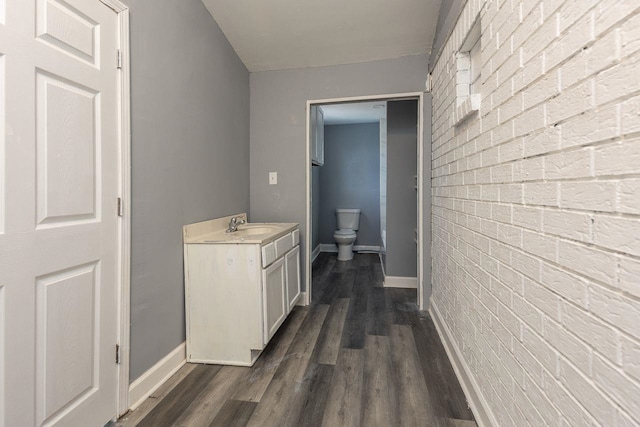 hallway featuring brick wall, dark hardwood / wood-style floors, and sink