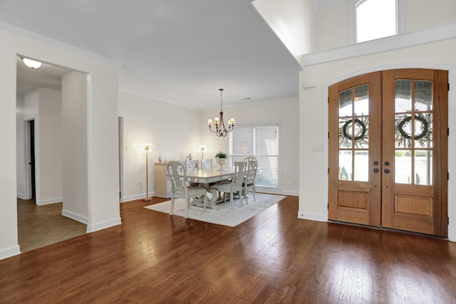 foyer entrance featuring a chandelier, dark hardwood / wood-style flooring, ornamental molding, and french doors