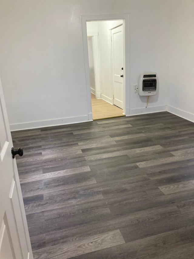 empty room featuring heating unit and dark hardwood / wood-style floors