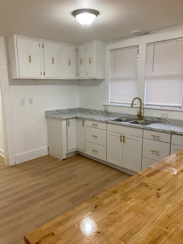 kitchen with sink, white cabinets, and light wood-type flooring