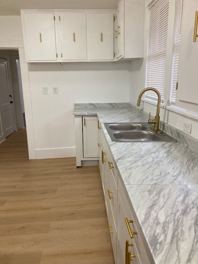 kitchen featuring white cabinets, light wood-type flooring, and sink