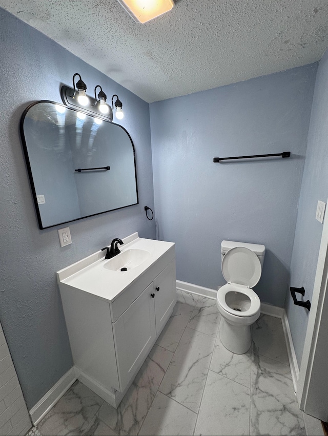 bathroom with vanity, toilet, and a textured ceiling