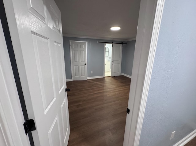 hall featuring ornamental molding, a barn door, and dark wood-type flooring