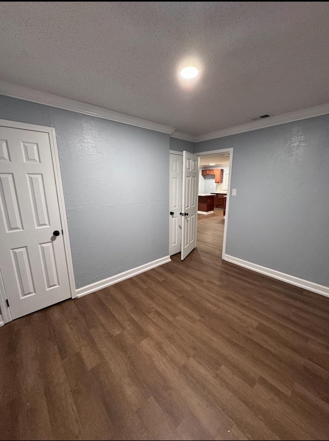 unfurnished room featuring dark hardwood / wood-style flooring, ornamental molding, and a textured ceiling