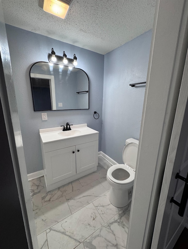 bathroom featuring a textured ceiling, vanity, and toilet