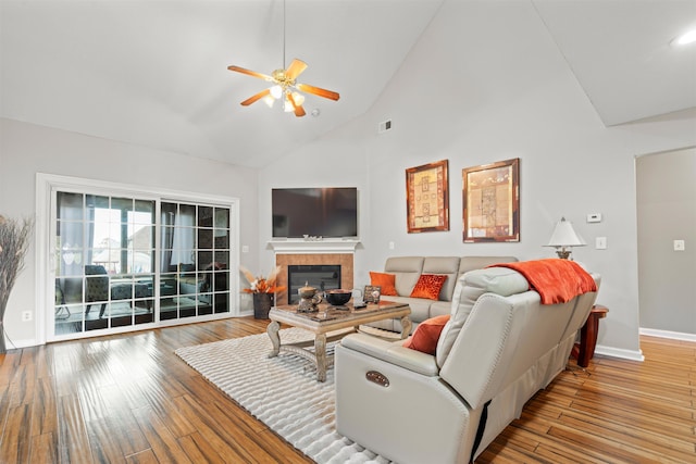 living room featuring a fireplace, light wood-type flooring, high vaulted ceiling, and ceiling fan