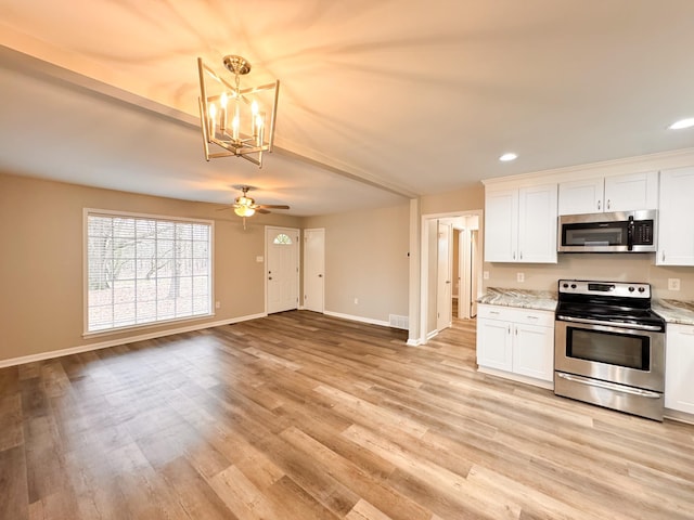 kitchen with appliances with stainless steel finishes, light wood-type flooring, light stone counters, pendant lighting, and white cabinetry