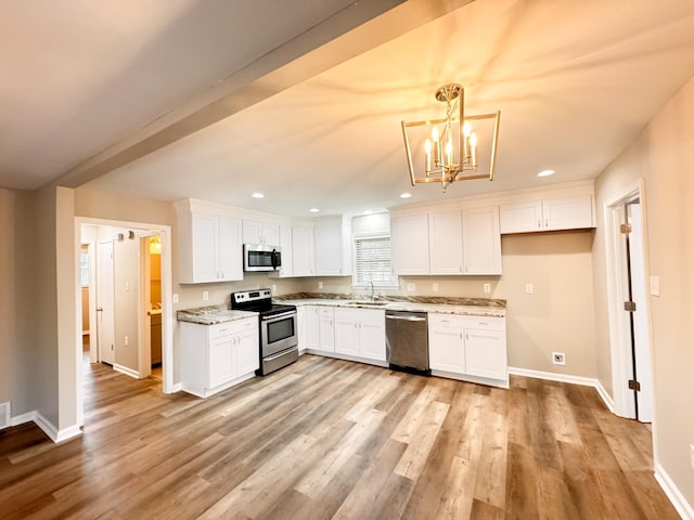 kitchen with pendant lighting, white cabinets, stainless steel appliances, and light wood-type flooring