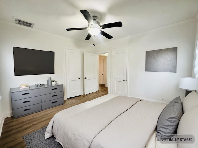 bedroom with crown molding, ceiling fan, and dark wood-type flooring