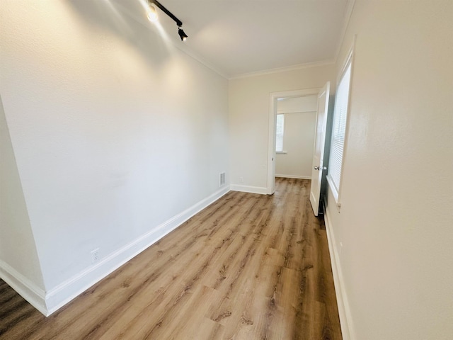 spare room with ornamental molding, rail lighting, and light hardwood / wood-style flooring