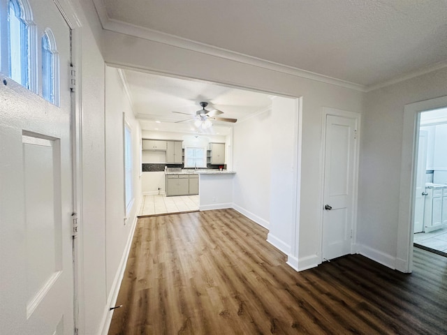 unfurnished living room with hardwood / wood-style flooring, ceiling fan, and crown molding