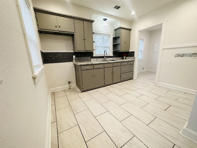 kitchen with gray cabinets, tasteful backsplash, and sink