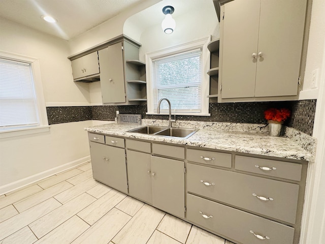 kitchen with tasteful backsplash, gray cabinets, and sink