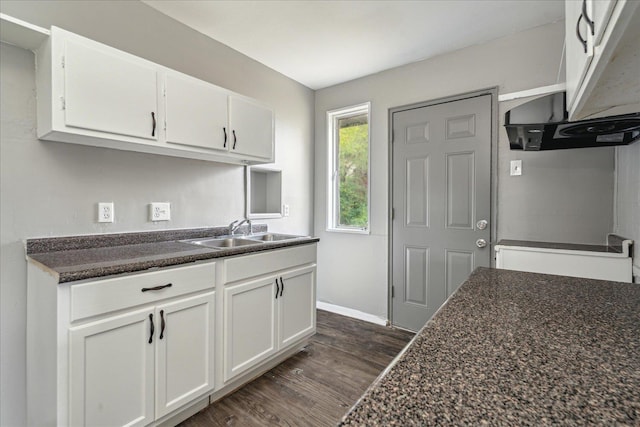 kitchen with white cabinets, dark hardwood / wood-style floors, dark stone countertops, and sink