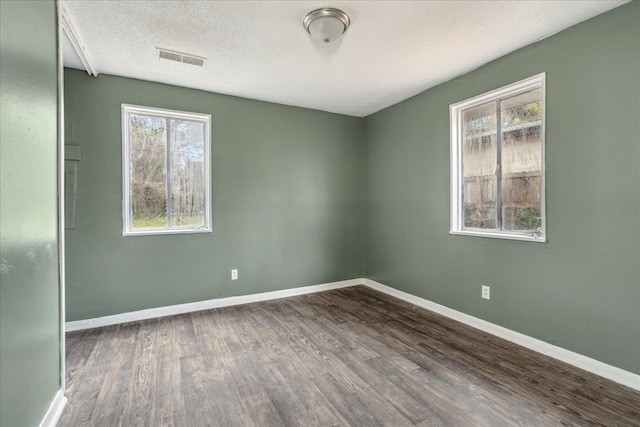 empty room with a textured ceiling and dark hardwood / wood-style flooring