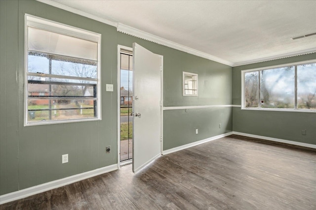 empty room featuring a textured ceiling, hardwood / wood-style flooring, and crown molding