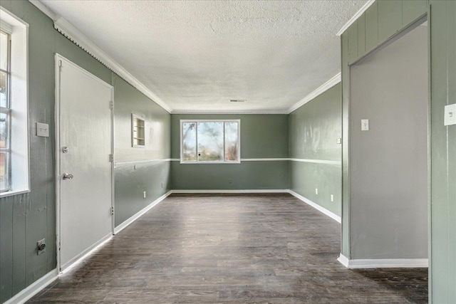 spare room featuring a textured ceiling, dark hardwood / wood-style floors, and ornamental molding