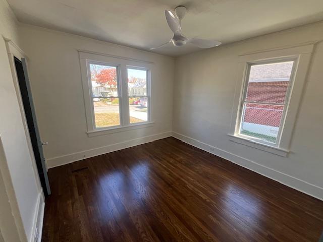 spare room featuring dark hardwood / wood-style floors, ceiling fan, and a healthy amount of sunlight