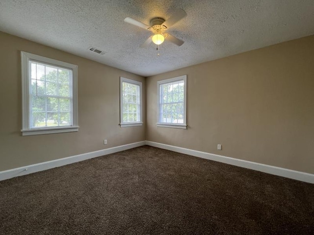 empty room with plenty of natural light, dark carpet, a textured ceiling, and ceiling fan