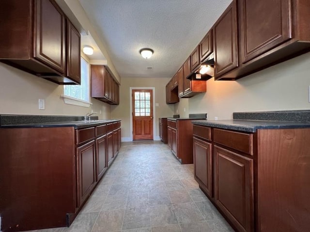 kitchen featuring sink, premium range hood, and a textured ceiling