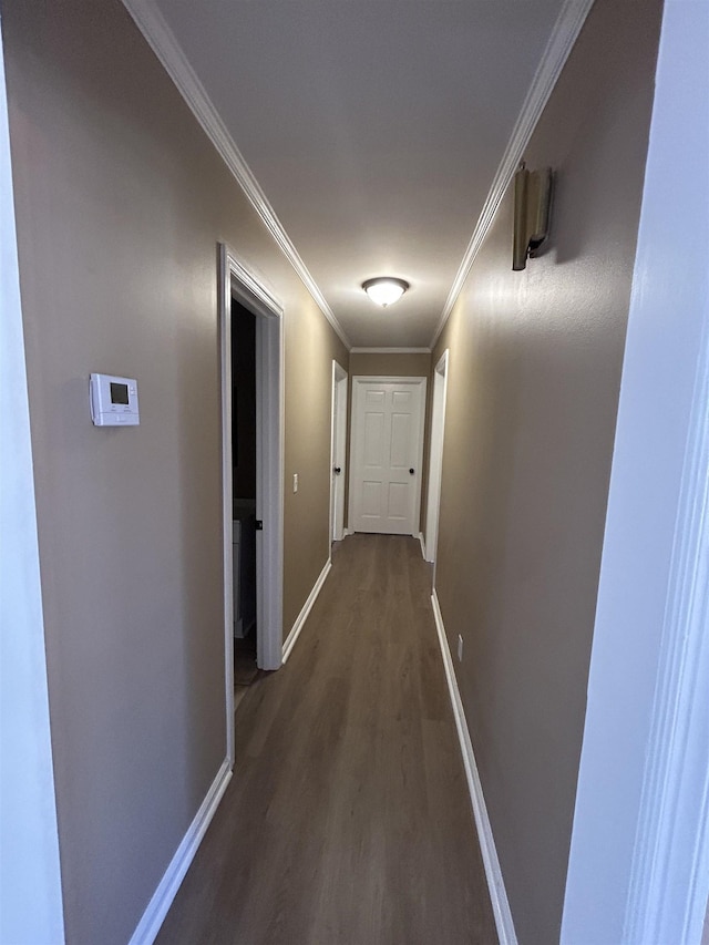 corridor with ornamental molding, dark wood finished floors, and baseboards