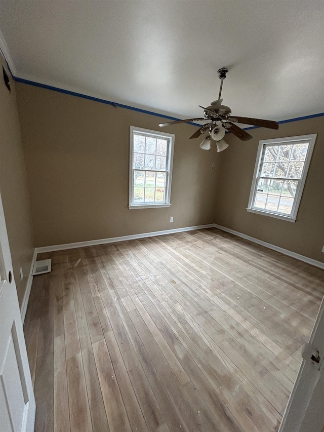 unfurnished room featuring plenty of natural light, baseboards, and wood finished floors