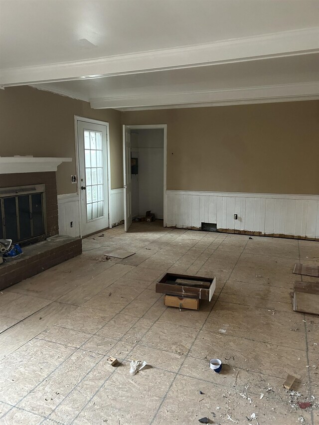 interior space with a brick fireplace, wainscoting, and beamed ceiling