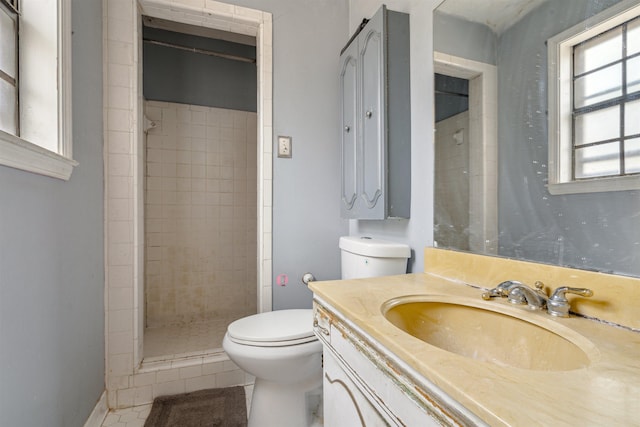 bathroom featuring tile patterned flooring, vanity, tiled shower, and toilet