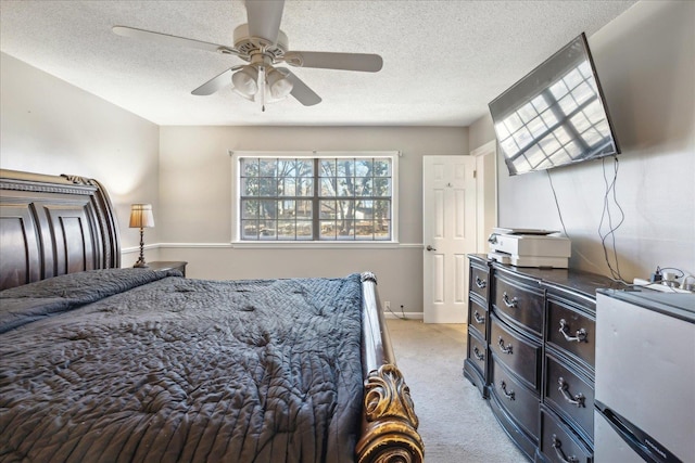 bedroom with ceiling fan, light colored carpet, and a textured ceiling