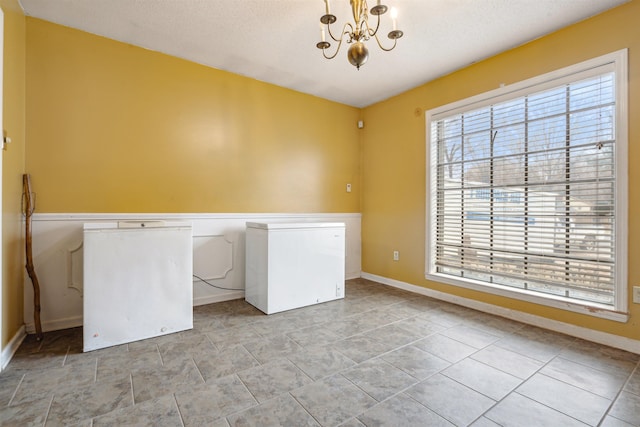 laundry room featuring a textured ceiling and a notable chandelier