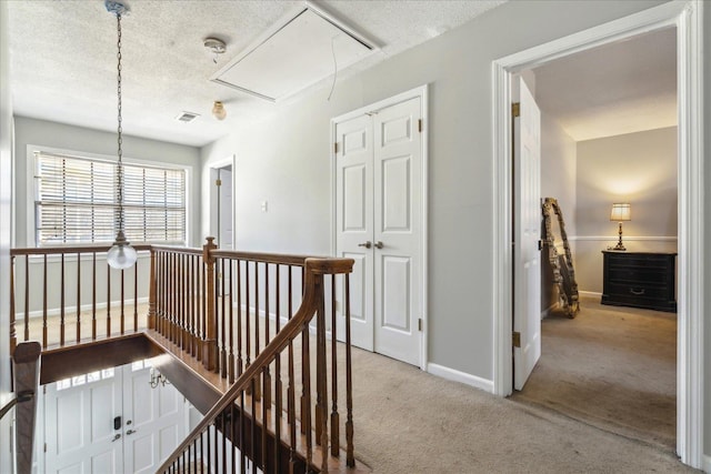 hallway with light carpet and a textured ceiling