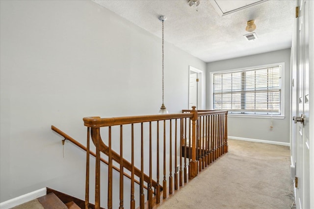 hallway with light carpet and a textured ceiling