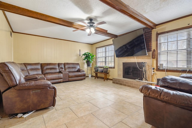 tiled living room with a fireplace, beamed ceiling, ceiling fan, crown molding, and a textured ceiling