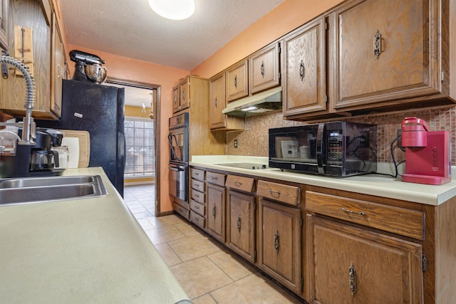 kitchen featuring light tile patterned flooring, sink, backsplash, black appliances, and a textured ceiling