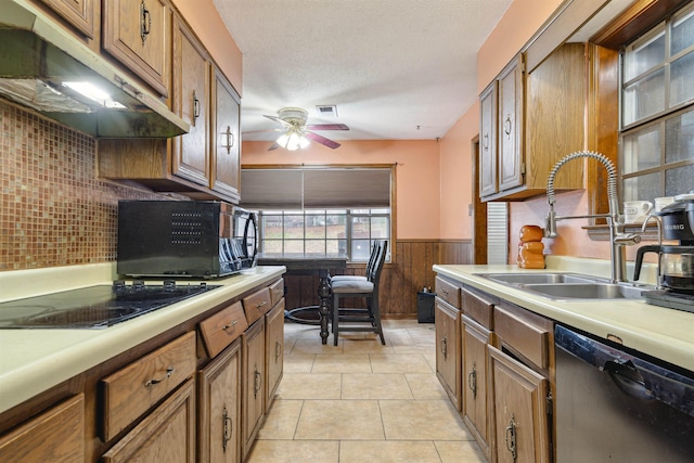 kitchen featuring light tile patterned flooring, sink, wood walls, ceiling fan, and black appliances