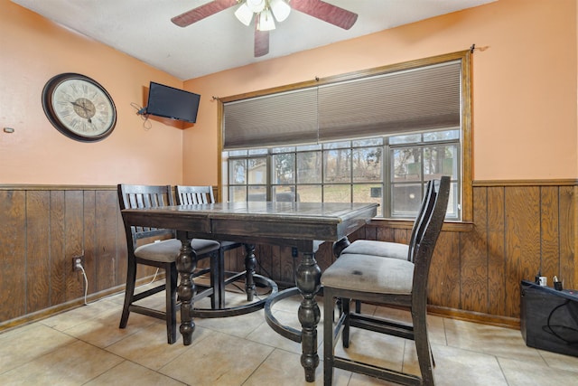 tiled dining area with ceiling fan and wood walls