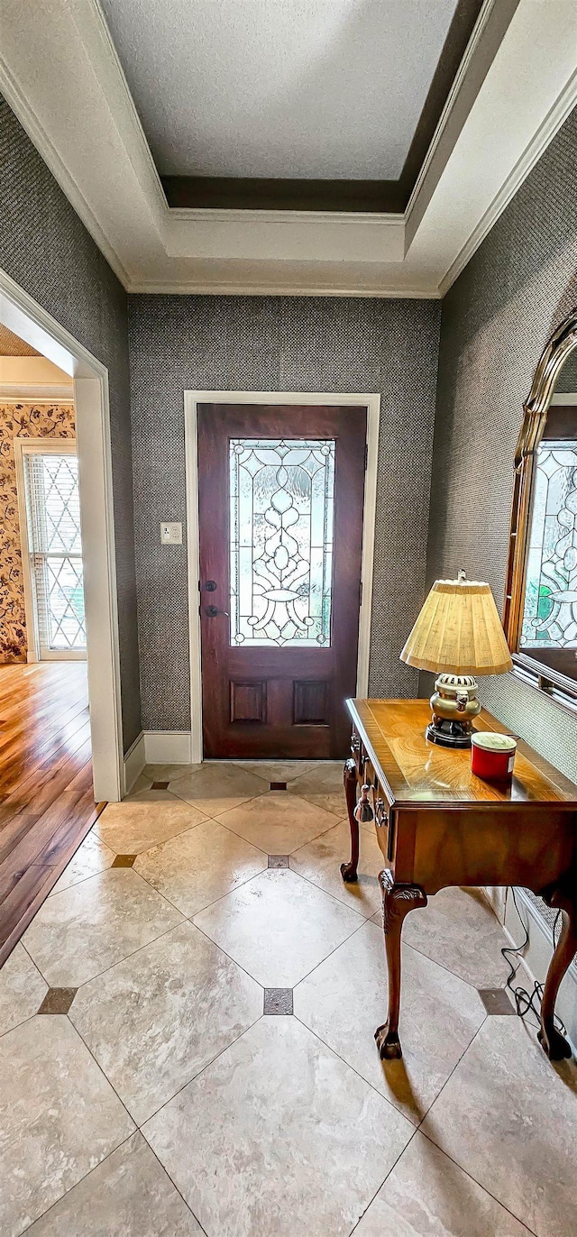 foyer featuring a healthy amount of sunlight, ornamental molding, and light hardwood / wood-style flooring