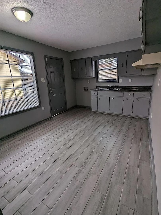 kitchen featuring a textured ceiling, gray cabinets, and light hardwood / wood-style flooring