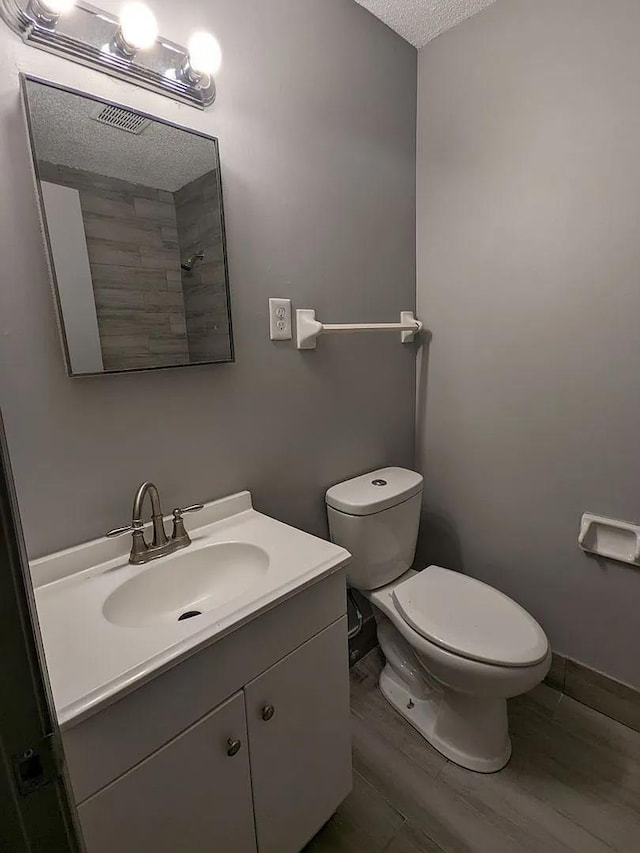 bathroom featuring vanity, toilet, wood-type flooring, and a textured ceiling