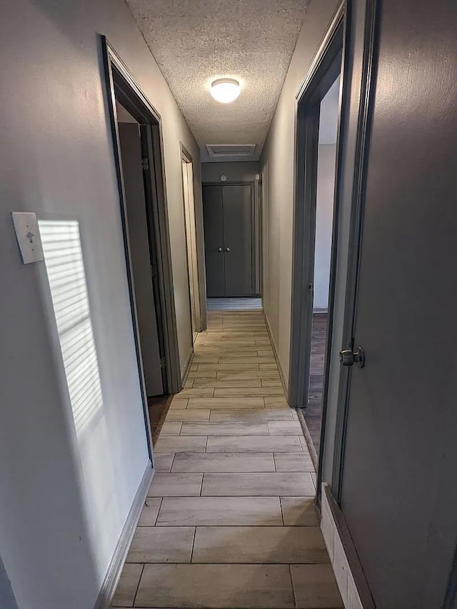 hallway with light hardwood / wood-style floors and a textured ceiling