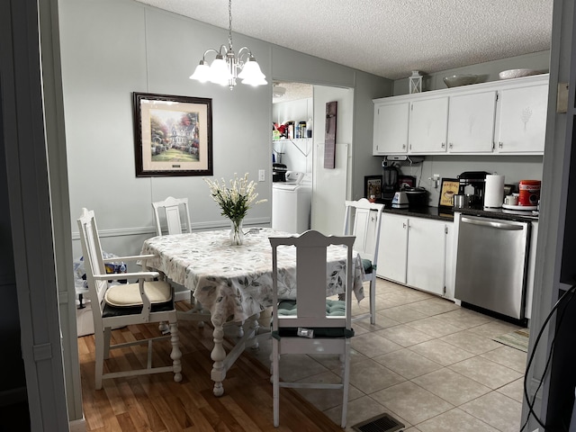 dining space featuring separate washer and dryer, a chandelier, a textured ceiling, and light wood-type flooring