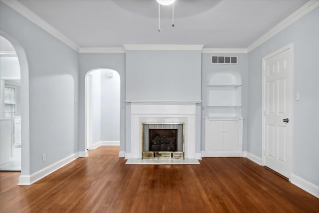 unfurnished living room featuring ceiling fan, built in features, wood-type flooring, and crown molding