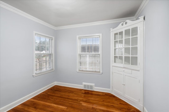 unfurnished room with hardwood / wood-style floors, a healthy amount of sunlight, and ornamental molding