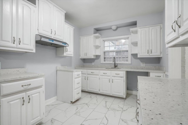 kitchen featuring light stone counters, white cabinetry, and sink