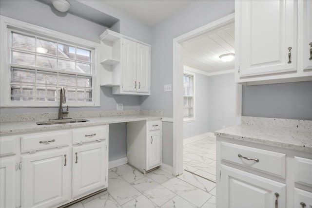 kitchen with light stone countertops, sink, and white cabinets