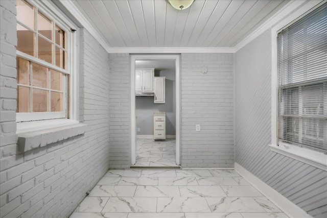 interior space with crown molding, plenty of natural light, and brick wall