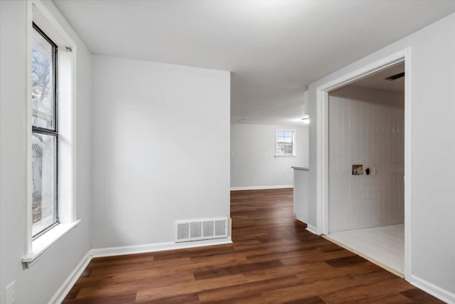 empty room featuring plenty of natural light and dark hardwood / wood-style flooring